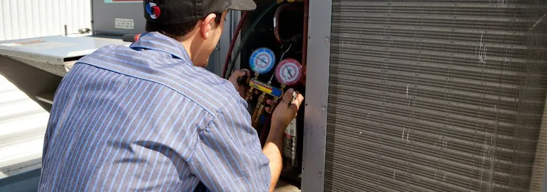 HVAC technician servicing a condenser unit in Satsuma