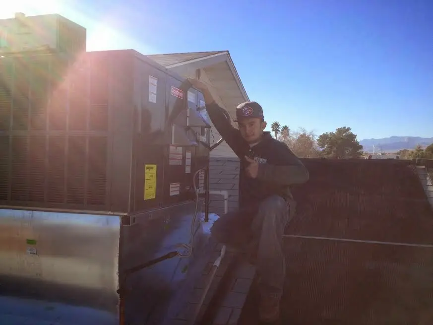 HVAC technician performing HVAC Inspection on a rooftop unit in Satsuma